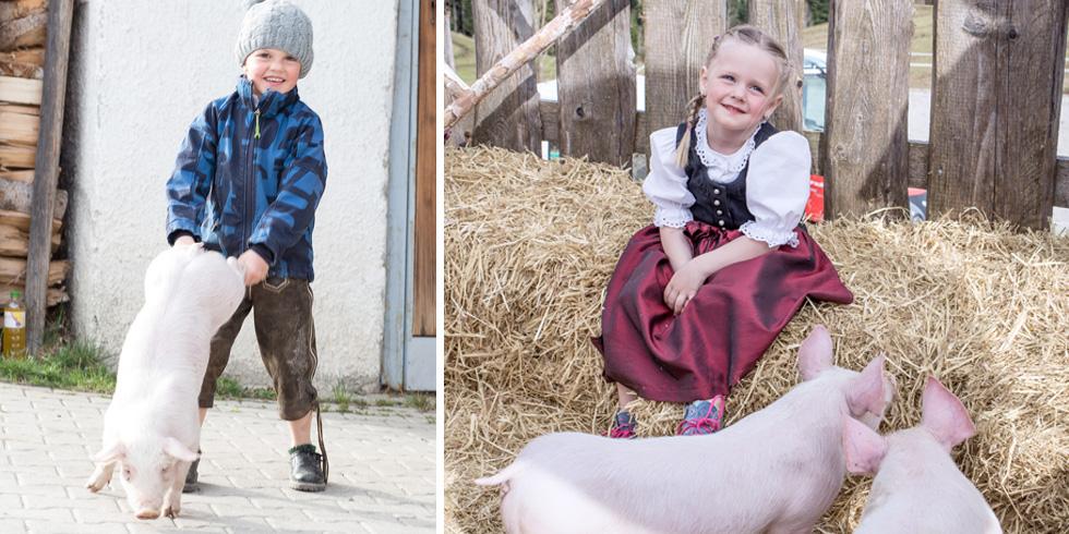 Kinder in Tracht mit den Minischweinen am Hof